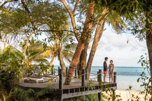 a couple standing on a dock next to the beach at Wellesley Resort Fiji in Vunaniu