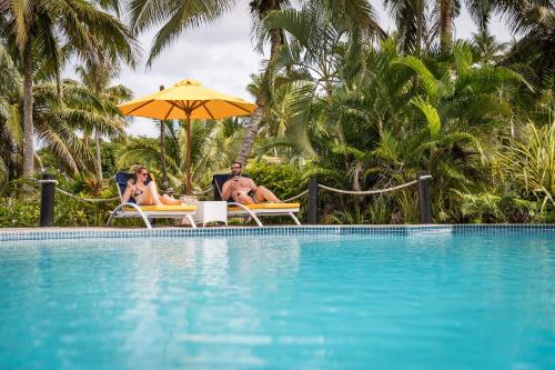 two people sitting in lawn chairs next to a swimming pool at Wellesley Resort Fiji in Vunaniu