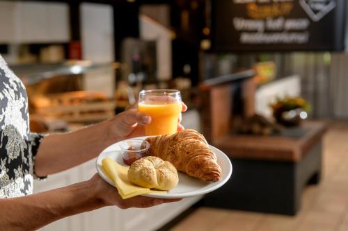 a person holding a plate of food and a glass of orange juice at Campanile Hotel & Restaurant Venlo in Venlo