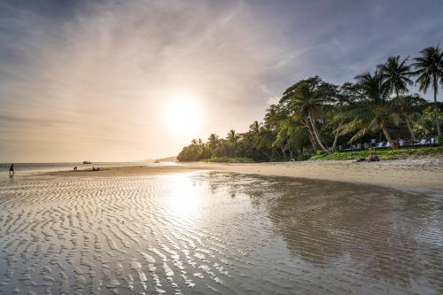a beach with palm trees and the sun setting at Wellesley Resort Fiji in Vunaniu