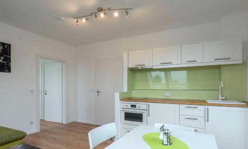 a kitchen with green and white cabinets and a table at WN Rooms in Wiener Neustadt