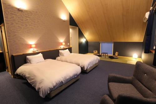ein Hotelzimmer mit 2 Betten und einem Stuhl in der Unterkunft Element in Nakafurano