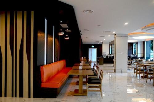 a restaurant with a red couch and tables and chairs at Avada Hotel in Trat