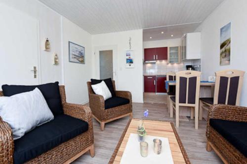 uma sala de estar com um sofá e cadeiras e uma cozinha em Ferienwohnung Perlmuschel em Bensersiel