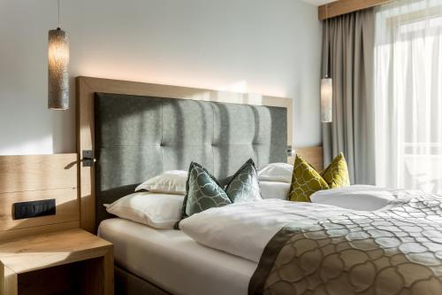 a bedroom with a large bed with colorful pillows at Hotel La Fradora - Dolomites Hotel in San Cassiano
