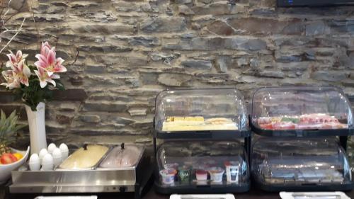three trays of food on a table with a stone wall at Hotel Ravene in Cochem