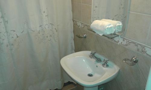 baño con lavabo y cortina de ducha en Hotel Victoria en Mar de Ajó