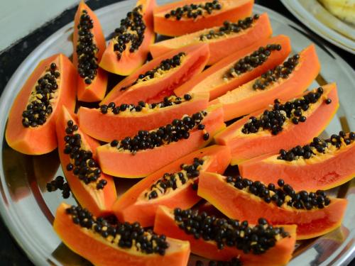 a plate topped with papaya slices with black seeds at Hotel Mais in Macapá
