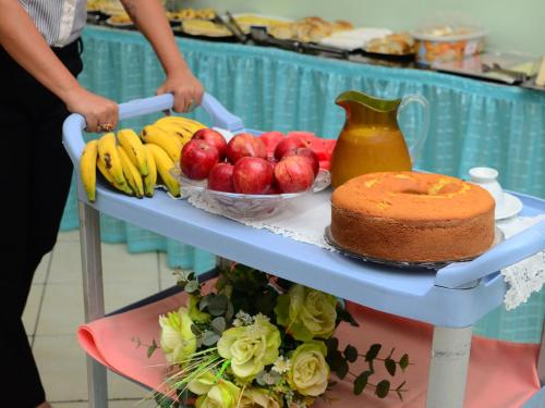 a table with a cake and fruit on it at Hotel Mais in Macapá