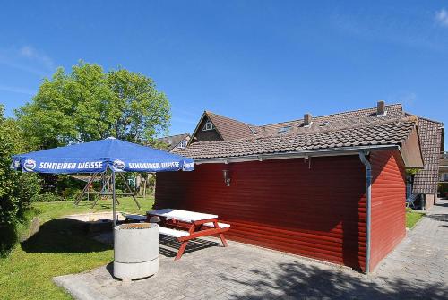 a smallshed with a picnic table and an umbrella at Landhaus Spittdiek in Neuharlingersiel