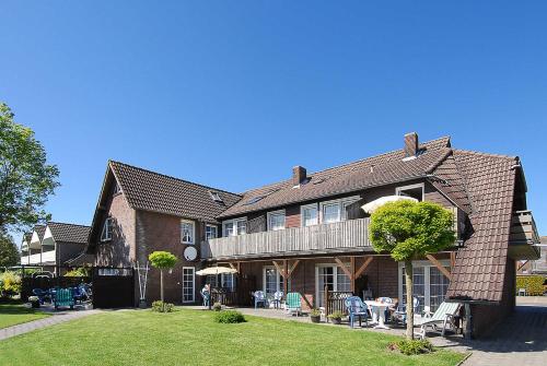 a large house with a yard with chairs and tables at Landhaus Spittdiek in Neuharlingersiel