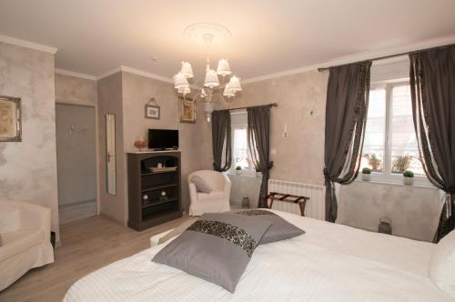a bedroom with a bed and a chair and a chandelier at Le Logis Aux Bulles in Verzy