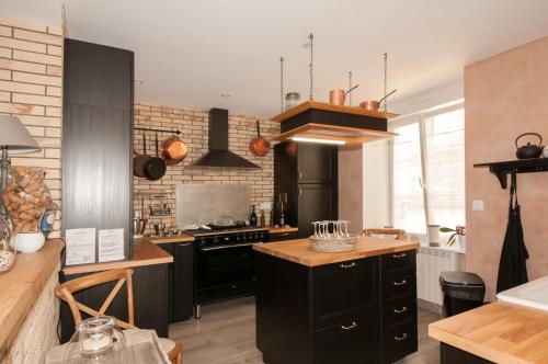 a kitchen with black cabinets and a brick wall at Le Logis Aux Bulles in Verzy