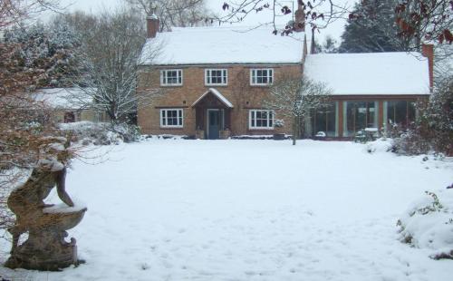 a house with a yard covered in snow at Lime Trees Farm in Bicester