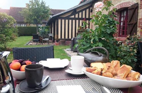 una mesa con un tazón de pan y un tazón de fruta en Le Pave d'Hotes, en Beuvron-en-Auge