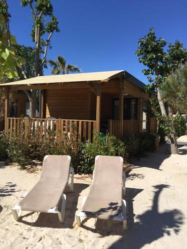 two lounge chairs on the sand in front of a house at Marino Mobilhomes in Grimaud