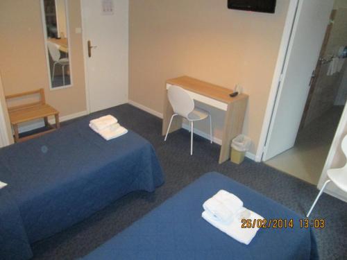 a room with a desk and a bed and a table at Hôtel-Restaurant Le Blueberry in Malaucène
