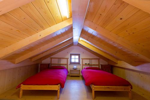two beds in a attic room with wooden ceilings at Chalet Champagne in Livigno