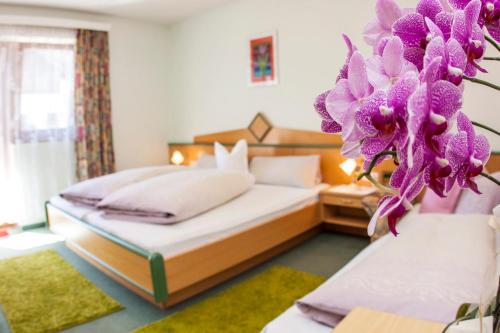 a hotel room with two beds and purple flowers at Frühstückspension & Ferienhaus Fädnerspitze in Galtür