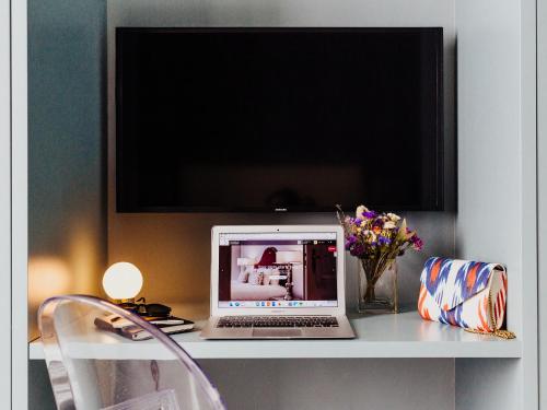 a laptop computer sitting on a desk with a tv at Dear Lisbon - Gallery House in Lisbon