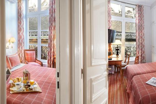 a room with two beds and a table with a tray of food at Relais Du Louvre in Paris