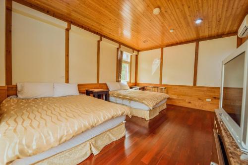 two beds in a room with wooden walls and wood floors at 溪頭鹿谷小半天春秋園民宿ChungQiu Yuan in Lugu