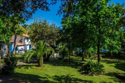 un parque con árboles y césped y una casa en Baia D'Oro, en Sabaudia