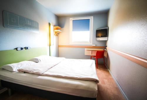 a small bedroom with a bed and a window at ibis budget Muenchen Ost Messe in Aschheim