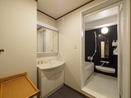 ein Bad mit einem Waschbecken und einem Spiegel in der Unterkunft 今日都 Kyoto Guesthouse in Kyoto