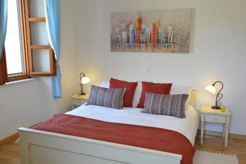 a bedroom with a bed with two lamps and a painting at Grandpa Mate House in Dragove