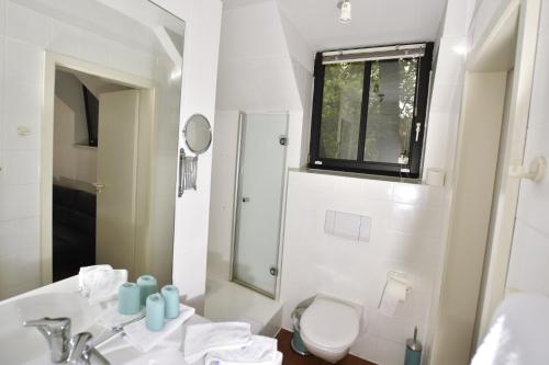 La salle de bains est pourvue d'un lavabo, de toilettes et d'un miroir. dans l'établissement Restaurant & Logis Steuerndieb, à Hanovre