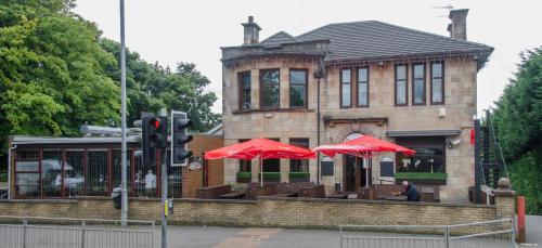 un edificio con dos sombrillas rojas delante de él en The Fullarton Park Hotel en Glasgow