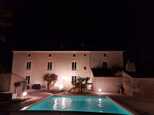 a large white building with a swimming pool at night at Le Marais Picotin in Saint-Pierre-le-Vieux