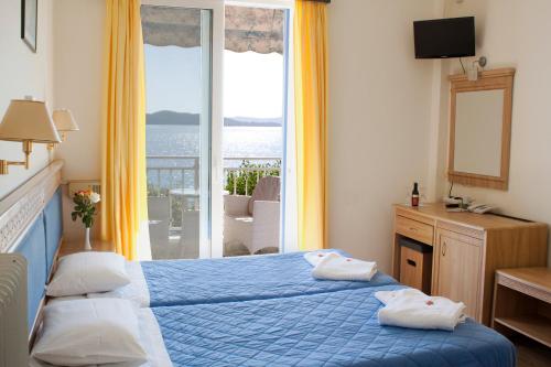 a bedroom with a blue bed with a view of the ocean at Hotel Nydri Beach in Nydri