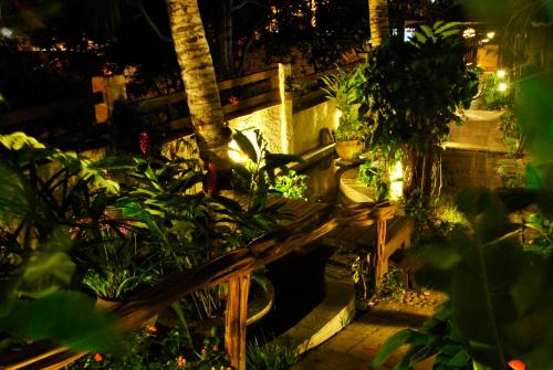 a wooden bench in a garden at night at Xamã Senses - Hotel Pousada in Pipa
