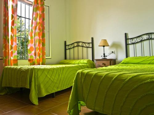 a bedroom with two beds with green sheets and a window at Casas Marin in Conil de la Frontera