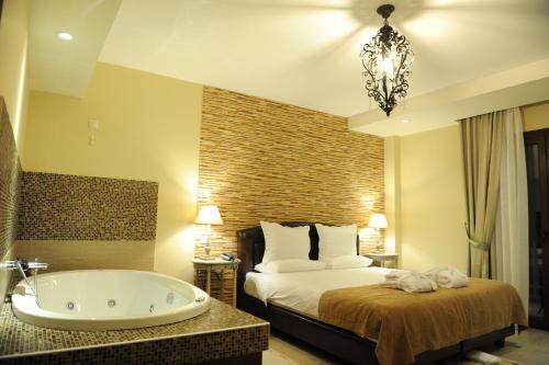 a bedroom with a bed and a tub in a room at Agapi Luxury Hotel in Kato Loutraki