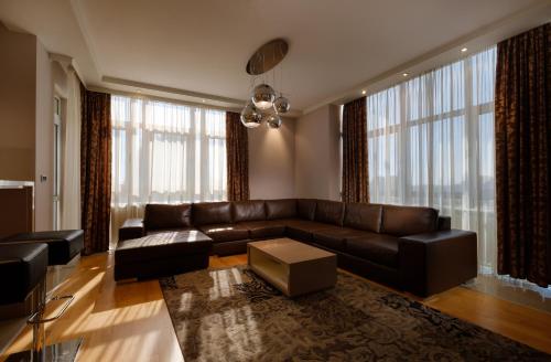 a living room with a leather couch and large windows at Apart K Apartments in Belgrade