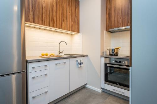 a kitchen with white cabinets and a sink at Apartamenty Tespis - Francuska Atal Park in Katowice