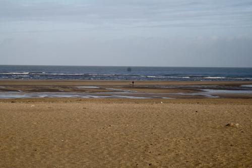 a beach with a person walking on the sand at La Maison de la Plage in Trouville-sur-Mer
