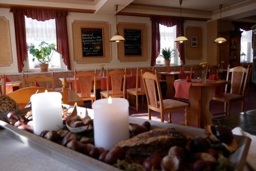 a table with candles in a restaurant with tables and chairs at Hotel Garni Brauhof Niederwiesa in Niederwiesa