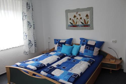 a bedroom with a bed with blue and white blankets and pillows at Ferienhaus Laydeckersch in Mastershausen