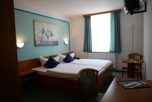 a hotel room with a bed with blue walls and a window at Hotel Garni Brauhof Niederwiesa in Niederwiesa