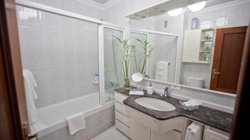 a bathroom with a sink and a shower and a tub at Apartamento Area Mayor in Malpica