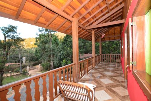 a wooden porch with a bench on a balcony at Pousada Florada da Serra in Monte Verde