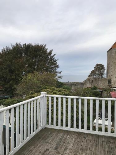 a wooden deck with a white fence and a building at Mullbärsgårdens Bed and Breakfast in Visby