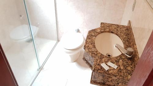 a bathroom with a toilet and a glass shower at Hotel Premier in Campo Grande