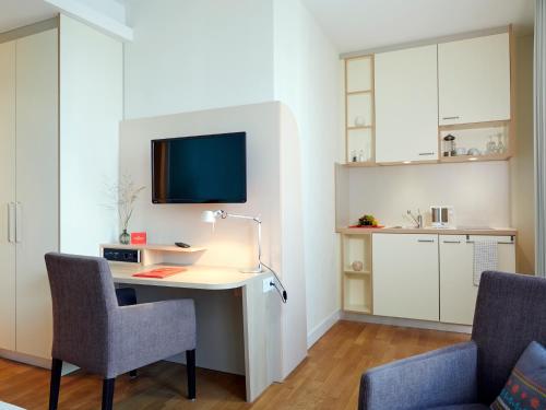a room with a desk and two chairs and a tv at Flottwell Berlin Hotel & Residenz am Park in Berlin