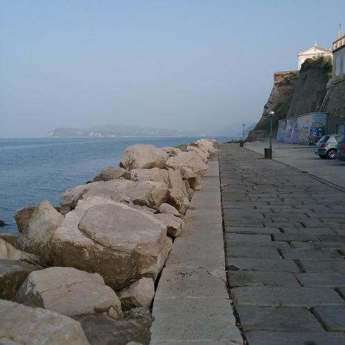 a stone sidewalk next to the water with a cliff at Bed and Brekfast Donatella in Piran