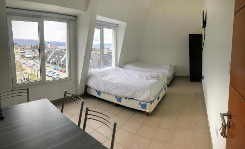 a room with a bed, table, chairs and a window at Patagonia Austral Apartamentos in Ushuaia